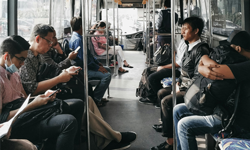 People on a bus sit facing the center aisle